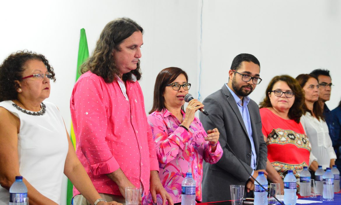 Professores que compõem a Gestão Superior da UEMASUL aparecem em pé, atrás de uma mesa, enquanto a Reitora fala segurando um microfone.