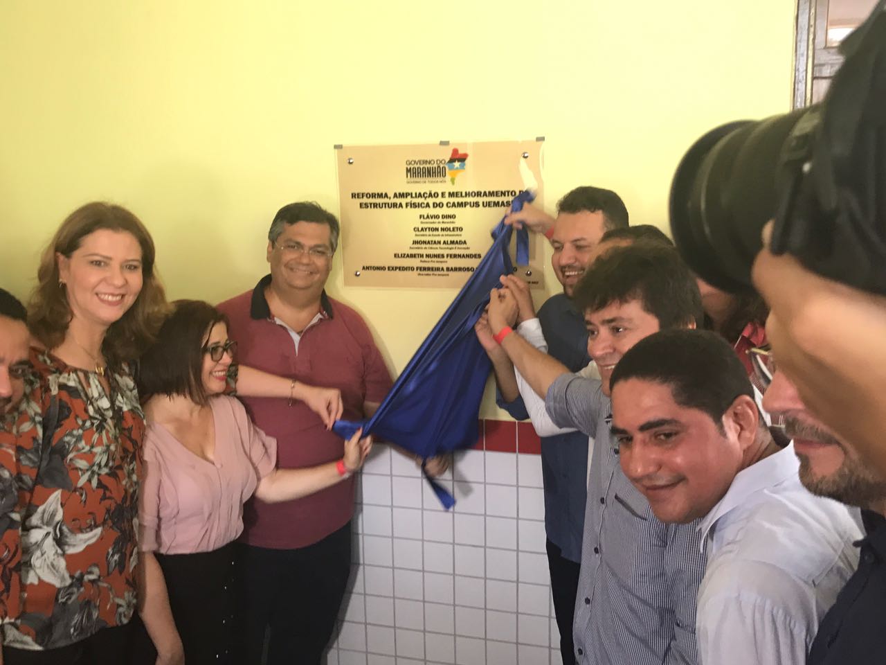 Governador, reitora da universidade e outras pessoas retiram tecido da placa inaugural na parede da universidade.