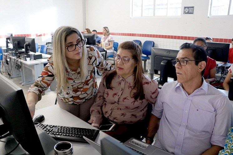 Integrantes da reunião, observando pautas a serem discutidas contidas em um computador.