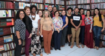 Professores reunidos em biblioteca discutem curricularização da extensão.