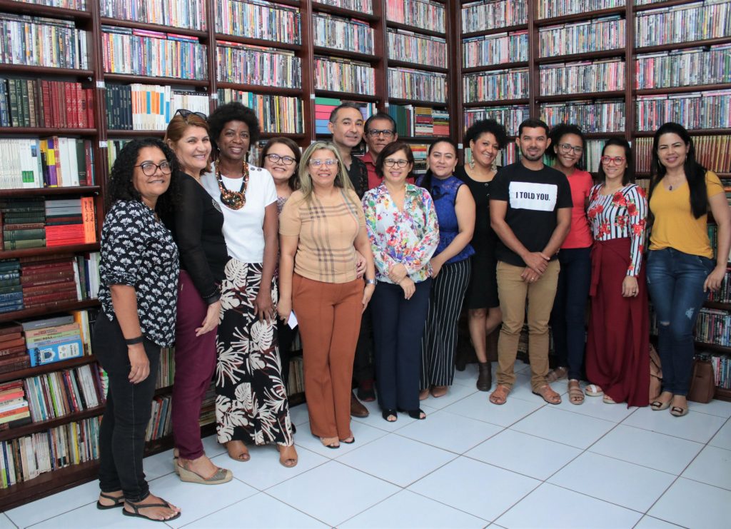 Professores reunidos em biblioteca discutem curricularização da extensão.