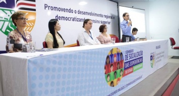 Professores reunidos no palco do auditório, entre eles está a reitora Elizabeth Nunes.