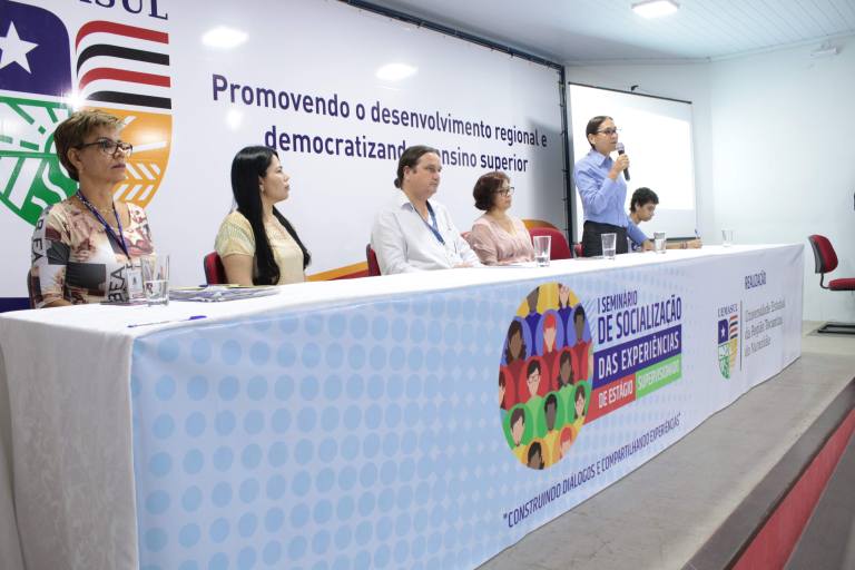 Professores reunidos no palco do auditório, entre eles está a reitora Elizabeth Nunes.