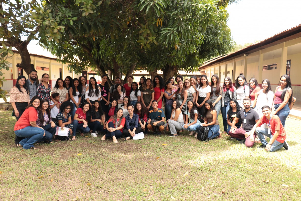 Os alunos da primeira turma de pedagogia aparecem posando debaixo de uma mangueira no pátio da universidade 