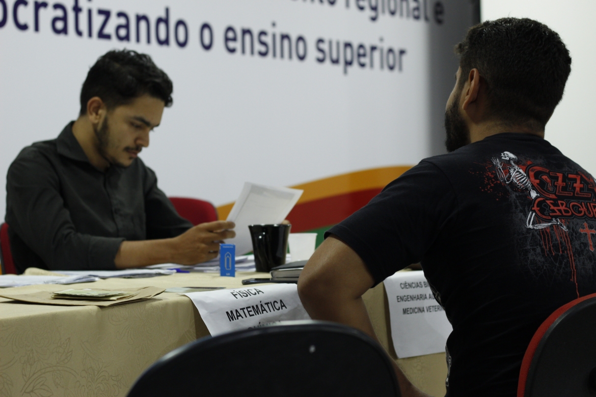 Estagiário da universidade realizando a matrícula de um calouro.